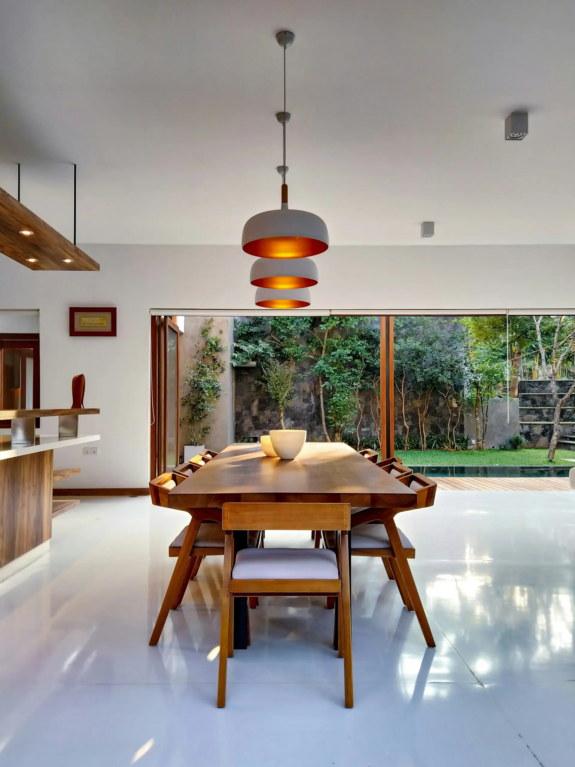 Sala de jantar com mesa de madeira maciça e cadeiras, aberta para um jardim
